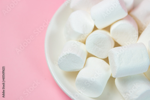 Plate with vanilla marshmallows on a pink background.