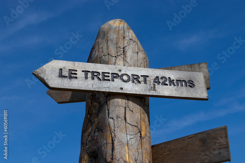 A wooden sign post with directions and distance to Le Treport in the Somme department of France. Travel and vacation concept. photo