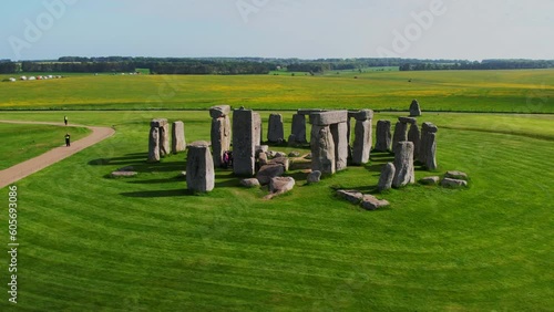 Drone aerial shot orbiting Stonehenge on a sunny day with tourists