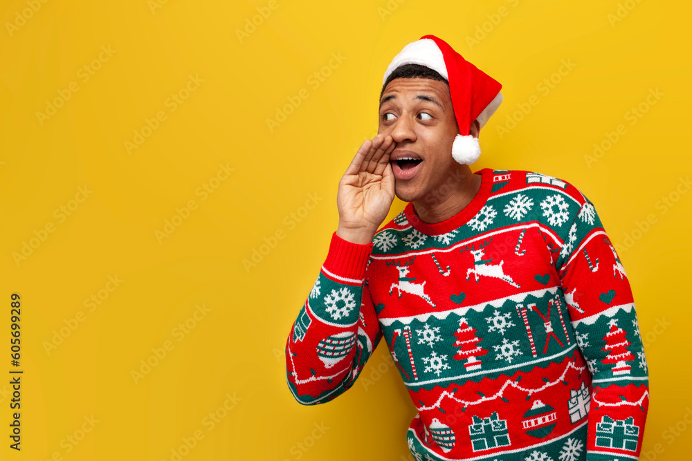 african american guy in new year clothes and santa hat sketches and speaks on yellow isolated background african american guy in new year clothes and santa hat sketches and speaks on yellow isolated background