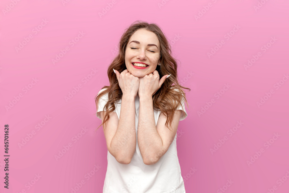young modest loving woman dreams and rejoices with her eyes closed on pink isolated background young modest loving woman dreams and rejoices with her eyes closed on pink isolated background