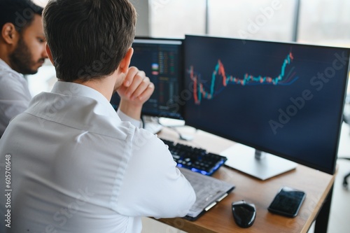 Two successful trader in formalwear pointing at display, analyzing stat and dynamic on forex charts, working in office together