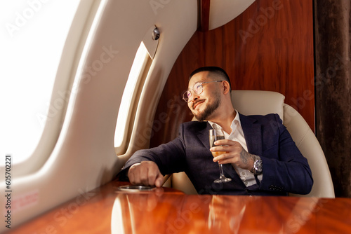 Fotografie asian businessman in suit and glasses with glass of champagne flies in private l