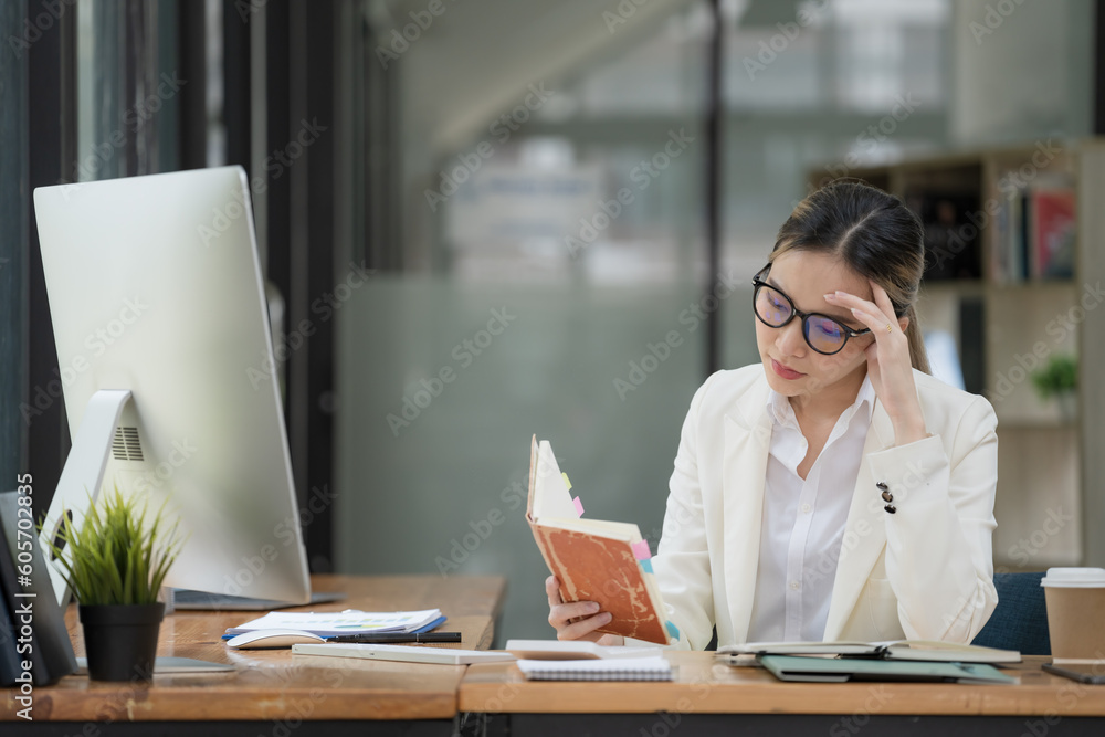An Asian businesswoman is serious about reading a book and works hard until the headache. An Asian businesswoman is serious about reading a book and works hard until the headache.