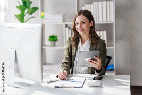 Concept of business office woman working,Businesswoman smile while working about her invesment plan with analyzing document and business investment graph data by using laptop on desk in workstation.