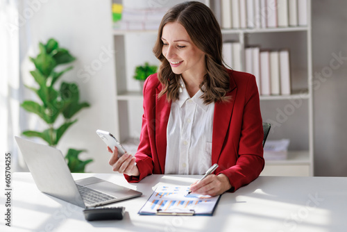 Concept of business office woman working,Businesswoman smile while working about her invesment plan with analyzing document and business investment graph data by using laptop on desk in workstation.