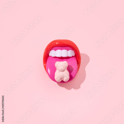 Red mouth with tongue sticking out, gummy bear on it, creative pop art layout, candy pink background. 