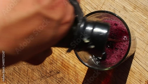 Indulge in the mesmerizing sight of a top-down view as rich Malbec wine flows gracefully from a demijohn into a glass. Experience the deep hues and exquisite aroma of this beloved wine variety.