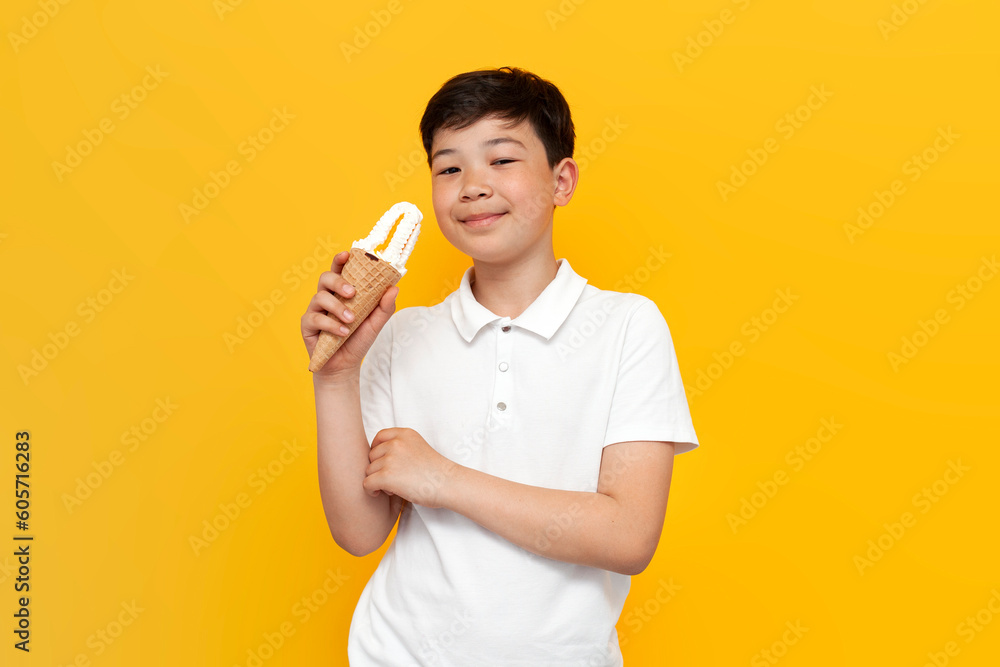 little asian boy holding ice cream and smiling on yellow background, korean kid with waffle cone eating sweet little asian boy holding ice cream and smiling on yellow background, korean kid with waffle cone eating sweet