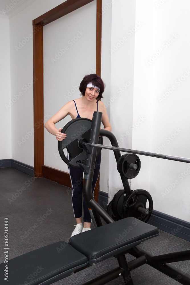 Fototapeta premium Woman athlete hangs a weight barbell.