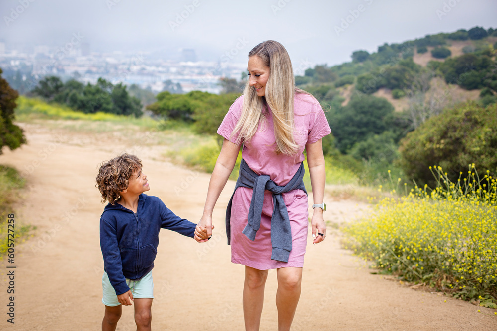 Φωτογραφία Mother and diverse son walking together holding hands outdoors at a hillside park near Los Angeles California