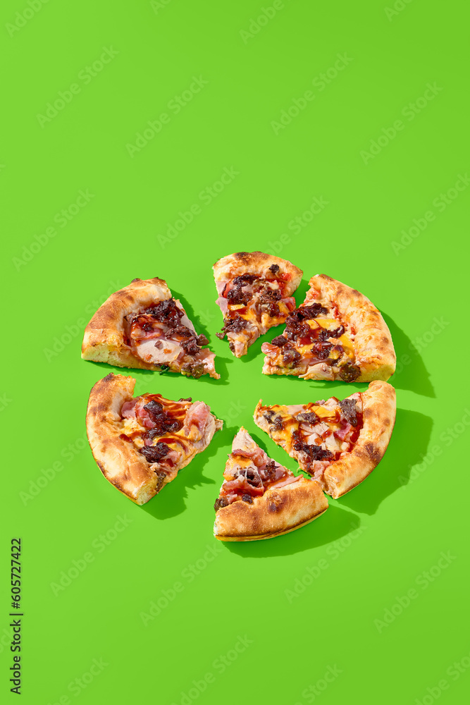 American pizza with thick crust, loaded with sausage, bacon, and marbled beef on a green background with sun shadows. The pizza is sliced into pieces, side view