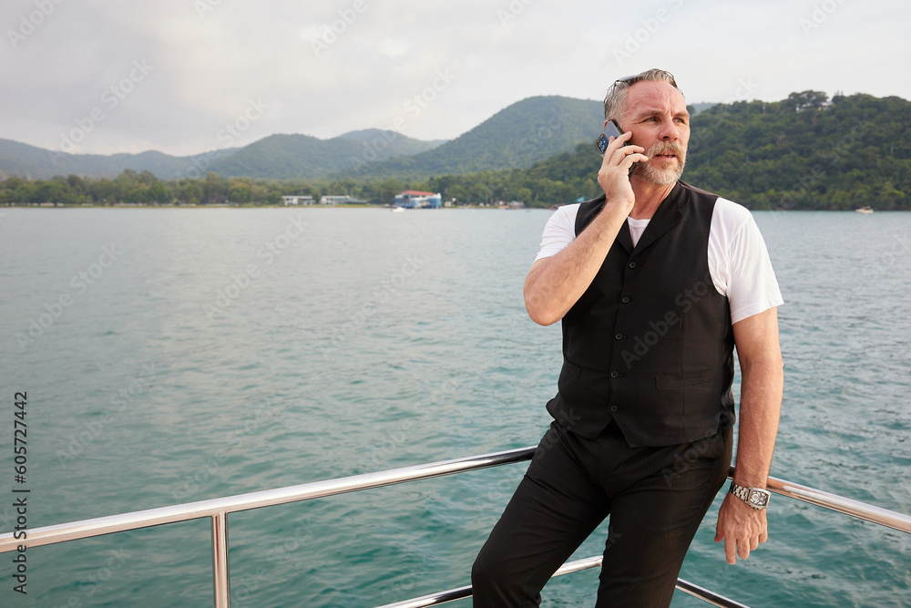 elderly man talking by smartphone in luxury yacht