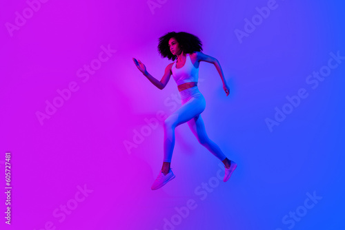 Full size profile photo of beautiful slim girl jump rush empty space ad promo leggings top shoes isolated on neon ultraviolet color background