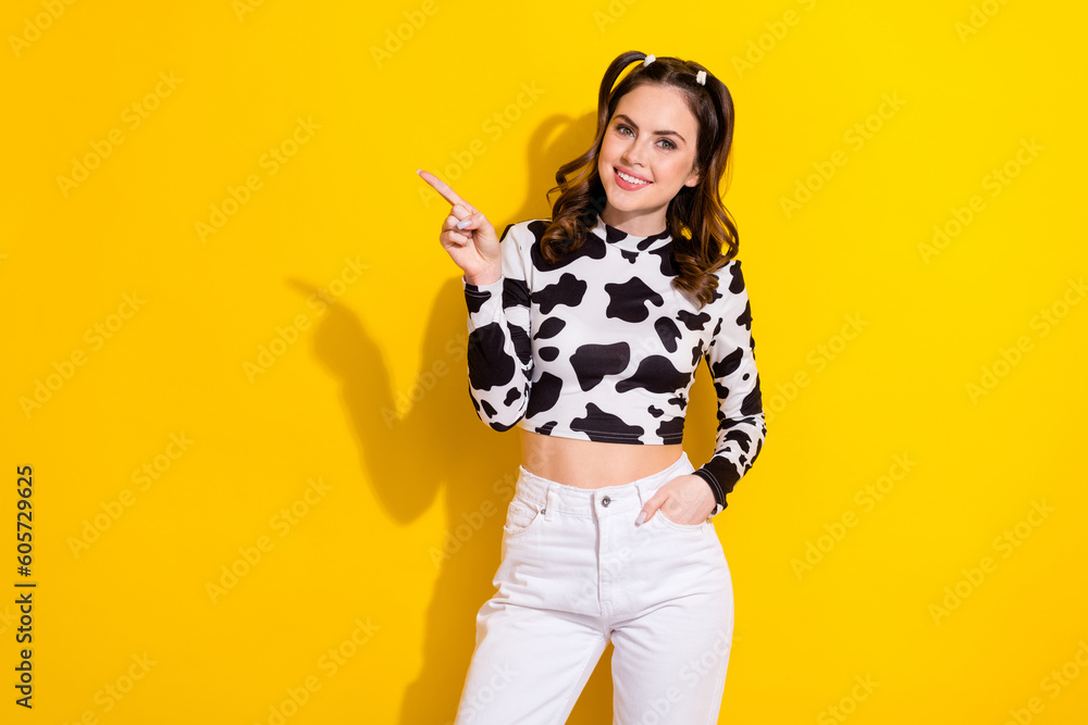 Photo of dreamy adorable girl wear cow skin shirt showing finger empty space isolated yellow color background Photo of dreamy adorable girl wear cow skin shirt showing finger empty space isolated yellow color background