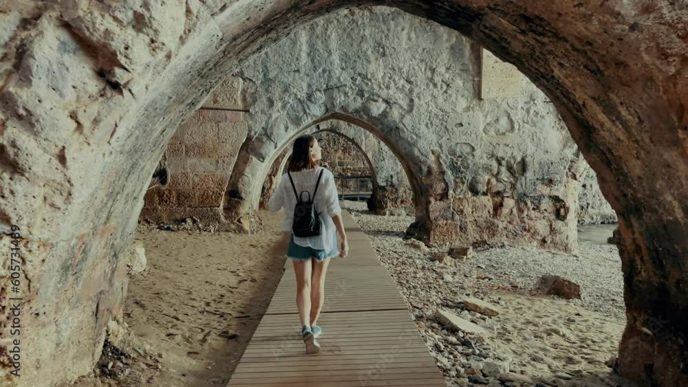 Girl tourist walks in ancient stone shipyard. Stone arches and walls. High quality 4k footage Girl tourist walks in ancient stone shipyard. Stone arches and walls. High quality 4k footage