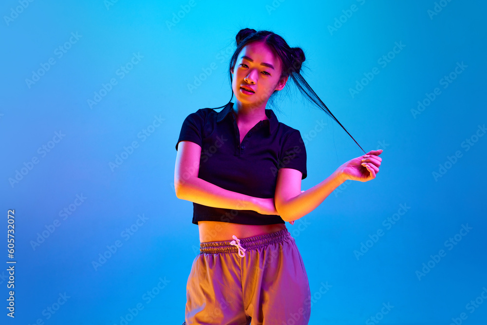 Portrait of beautiful, young, korean girl with stylish hairstyle, in casual clothes posing against blue background in neon light. Concept of emotions, facial expression, youth, lifestyle, inspiration Portrait of beautiful, young, korean girl with stylish hairstyle, in casual clothes posing against blue background in neon light. Concept of emotions, facial expression, youth, lifestyle, inspiration