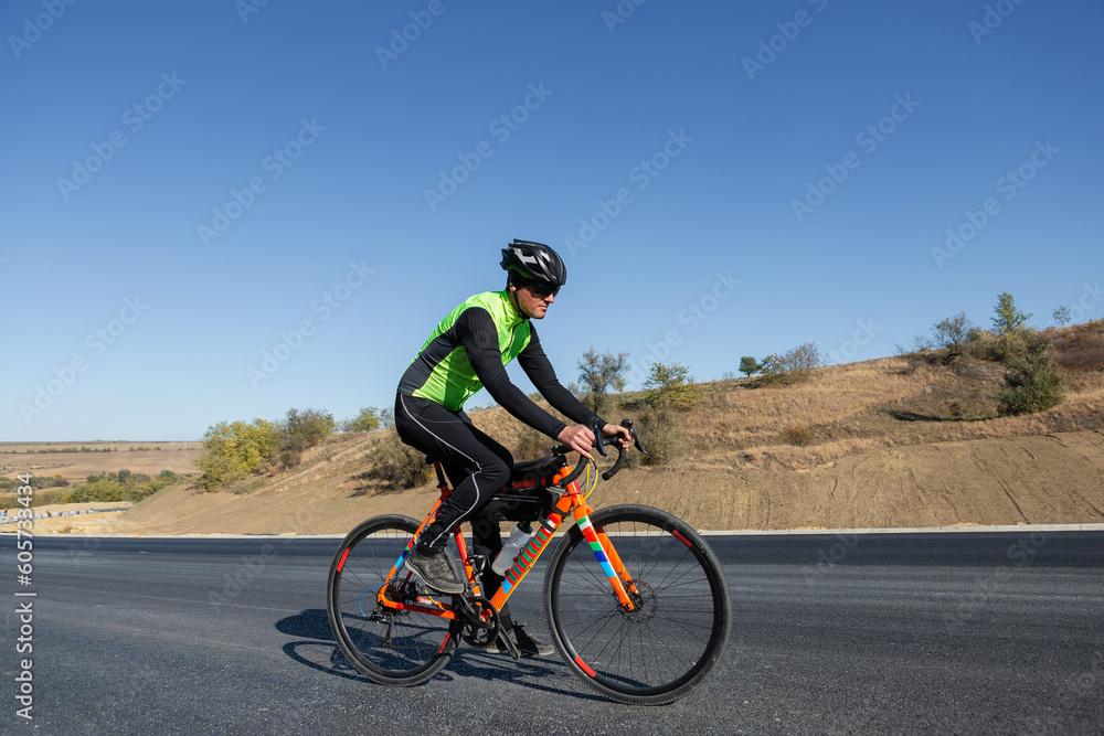 Fototapeta premium Cyclist riding bicycle on road against clear sky