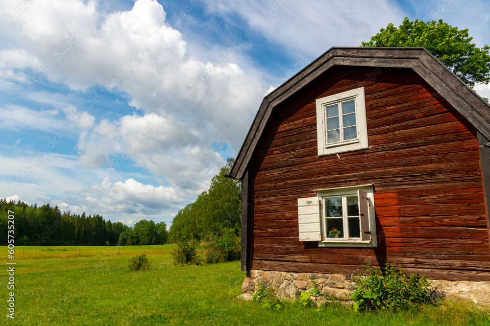 Old traditional red house on a swedish farm on a sunny summer day with clouds in the sky.
