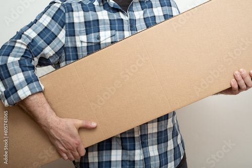 Man hand holding a long size cardboard box of new furniture set. Delivering concept.