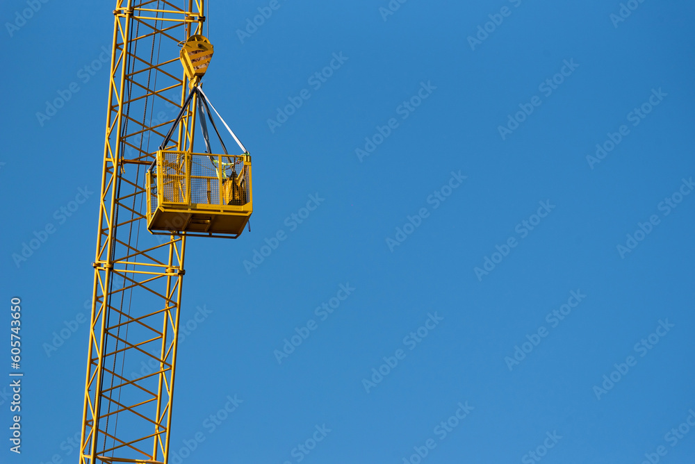 Construction crane with basket against the blue sky. Construction crane with basket against the blue sky.