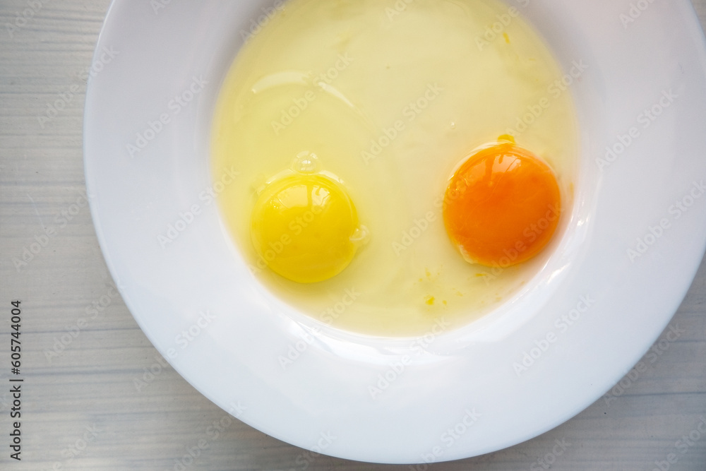 Raw eggs in a white plate. Yolks of different colors Raw eggs in a white plate. Yolks of different colors