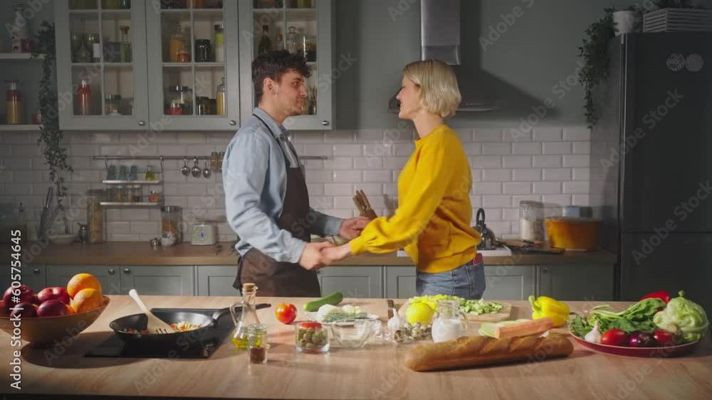 Slow motion. Happy young couple dancing in the kitchen, preparing meal for romantic dinner together Slow motion. Happy young couple dancing in the kitchen, preparing meal for romantic dinner together
