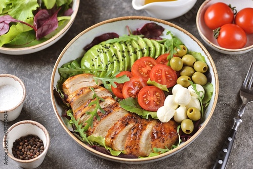 Healthy salad with grilled chicken breast, mozzarella, avocado, olives and cherry tomatoes