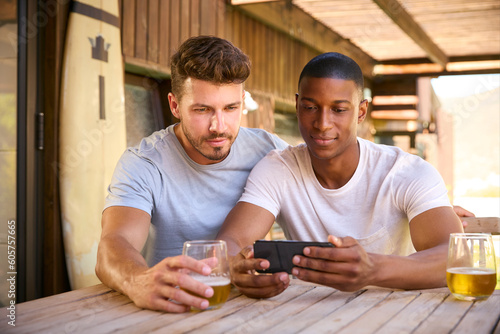 Two Male Friends Outdoors At Home Watching Sports Action On Mobile Phone