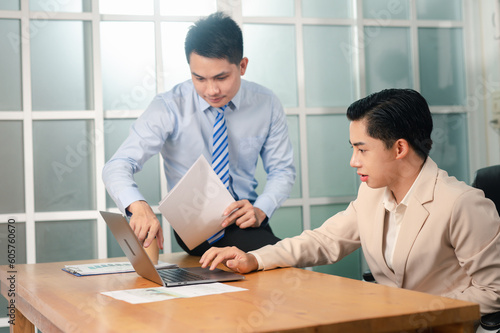 Image of two young of smart businessmen discussing project at meeting