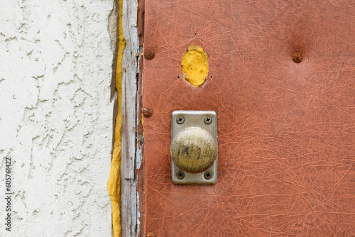 Old brown door with a metal handle, part of a white decorative facade.