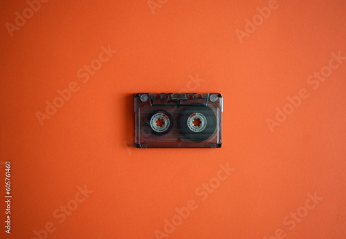 Audio cassette in the middle on an orange background, top view.