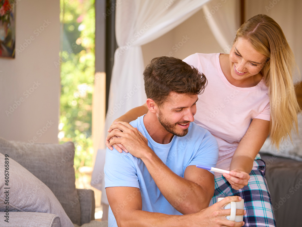 Fototapeta premium Excited Couple In Bedroom At Home Celebrating Positive Pregnancy Test Result
