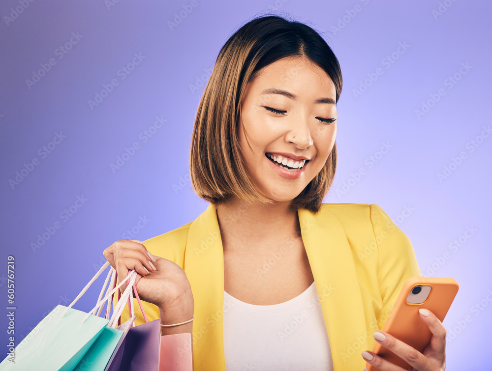 Asian woman, phone and shopping bag in studio, texting and smile for deal, sale or discount by background. Japanese girl, retail and happy with social media, contact and luxury by purple background