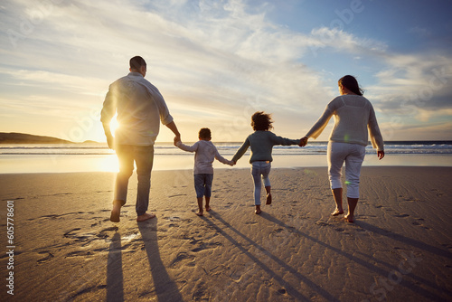 Sunset, beach and back of family holding hands and walking on holiday, summer vacation and weekend. Nature, travel and mother, father and children by ocean for bonding, adventure and quality time