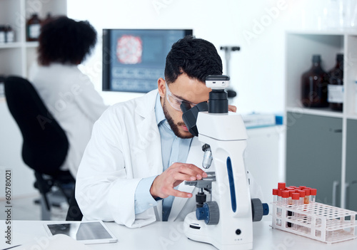 Science, particles and scientist analyzing with a microscope in a medical laboratory with concentration. Biotechnology, pharmaceutical and male researcher working on scientific project for healthcare