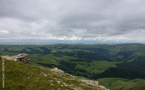 Fantastic dramatic landscape - panoramic view of the hilly valley blurred in the morning fog from the Bermamyt plateau in Karachay-Cherkessia on a cloudy summer day