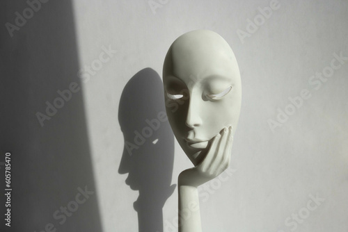 A statuette with the face of a young girl on her arm stands on a white background