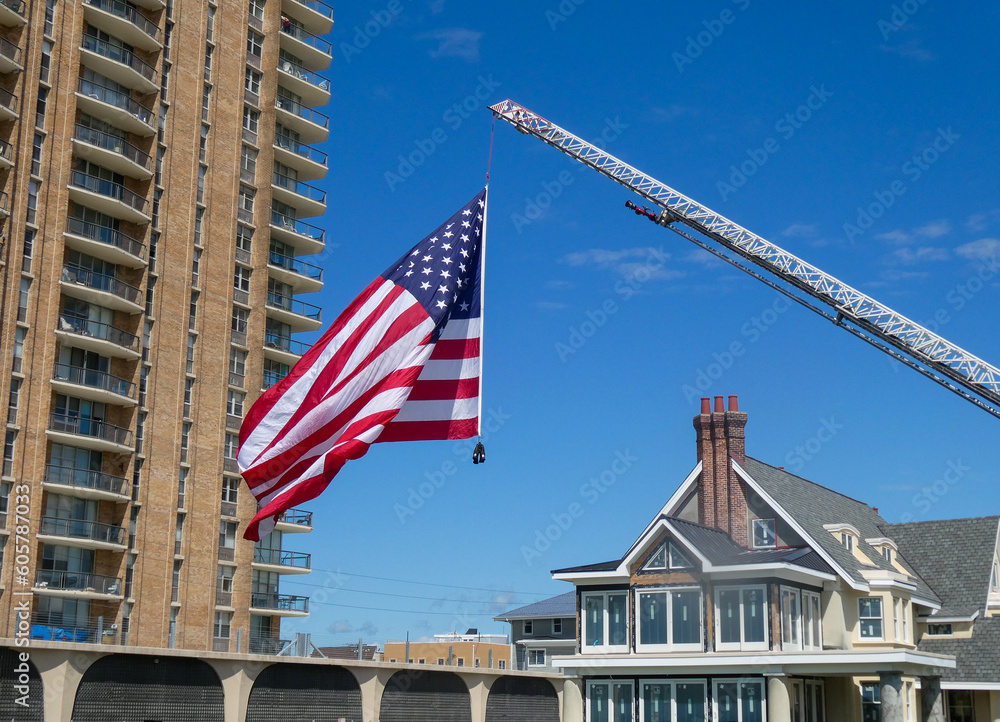 Large American Flag handing from a fire truck ladder weighed down by firefighter boots