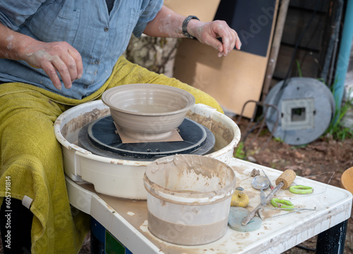 Making of mud pot on potters wheel during workshop outdoor