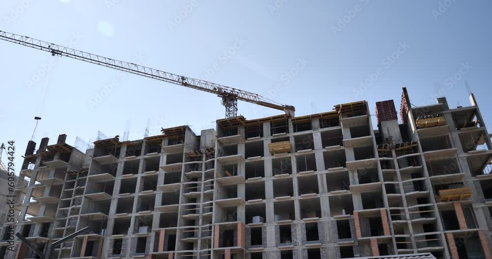 Slow view of the construction of a high-rise building, over the monolithic reinforced concrete house hangs a truck crane. An empty box of a house with no windows, doors or walls. Slow view of the construction of a high-rise building, over the monolithic reinforced concrete house hangs a truck crane. An empty box of a house with no windows, doors or walls.