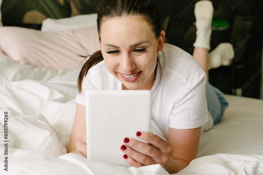 Happy woman using tablet in bedroom at home Happy woman using tablet in bedroom at home