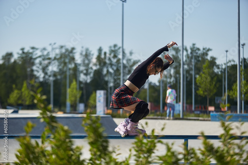Young roller blader female grinding on a rail in a skatepark. Cool aggressive inline skater person performing a grind trick in a concrete urban park