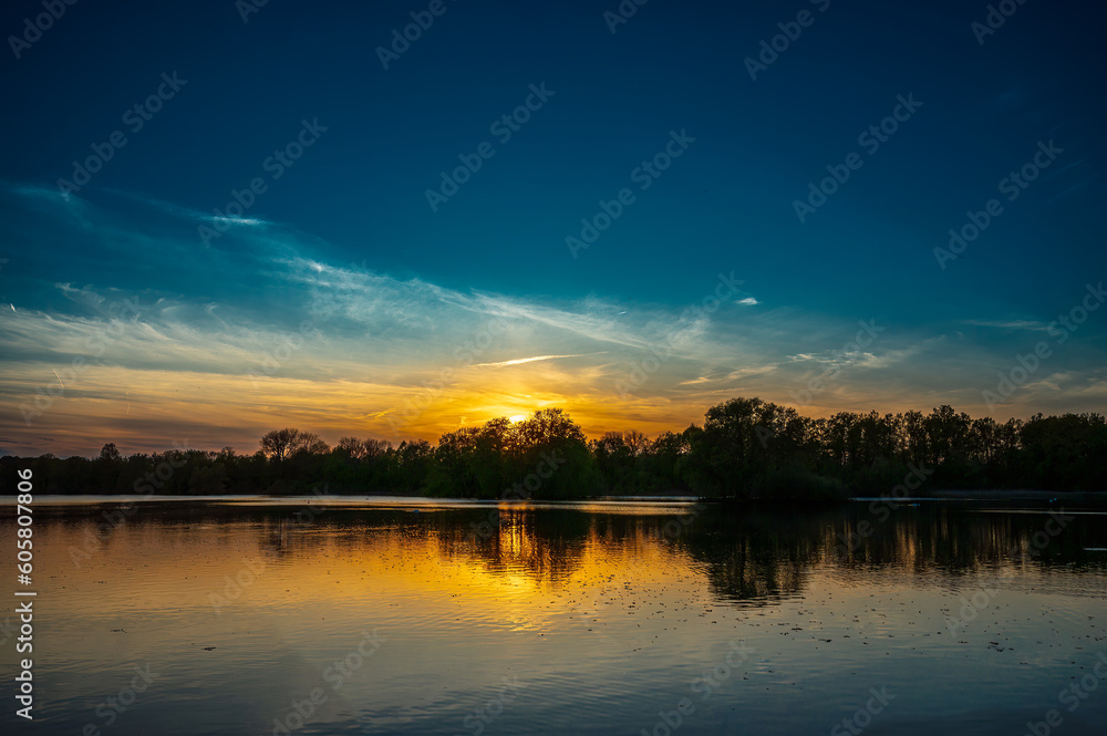 Fototapeta premium The sun sets over the lake.