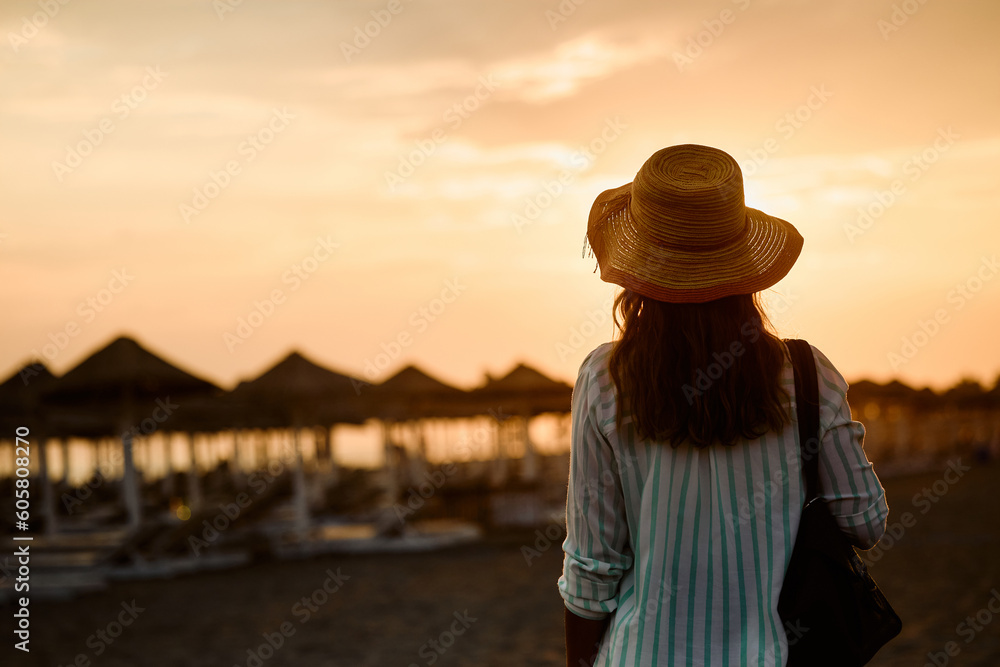 Back view of woman on beach at sunset during summer.