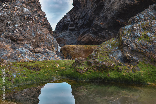 rockpools and reflections in water with coastal cliffs on summer beach
