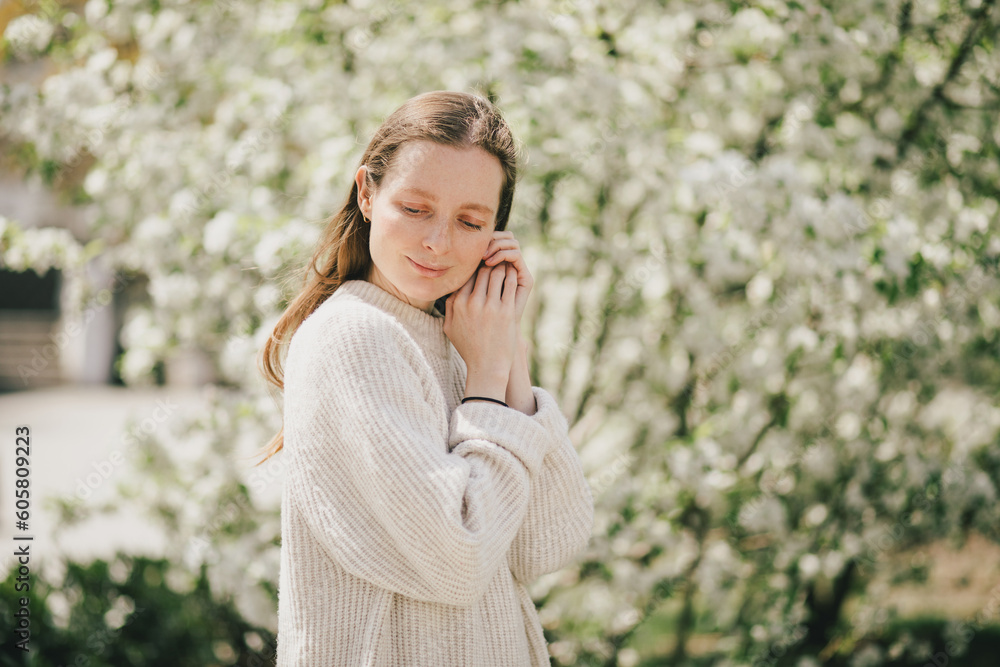 Young beautiful woman with freckles near blooming spring trees. Young beautiful woman with freckles near blooming spring trees.