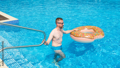 young man with rubber ring in suumer swimming pool  photo