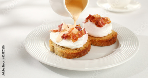 poached egg toast topped with hollandaise sauce. benedict egg. serving breakfast on a white background. sunny day. angle view.