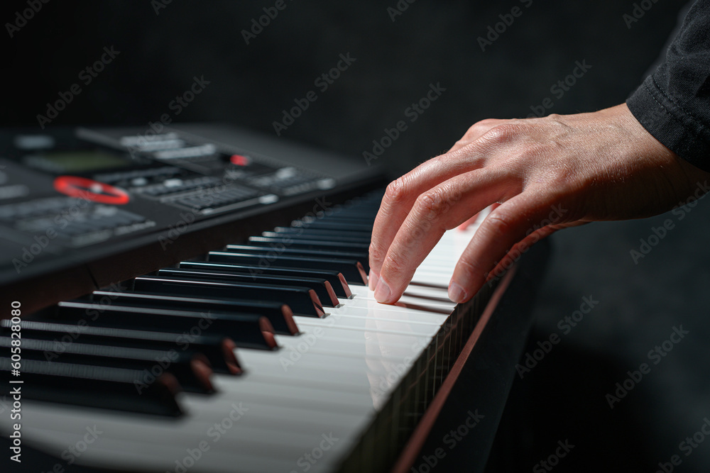 Obraz premium Playing a synthesizer on a dark background. The musician plays the synthesizer.